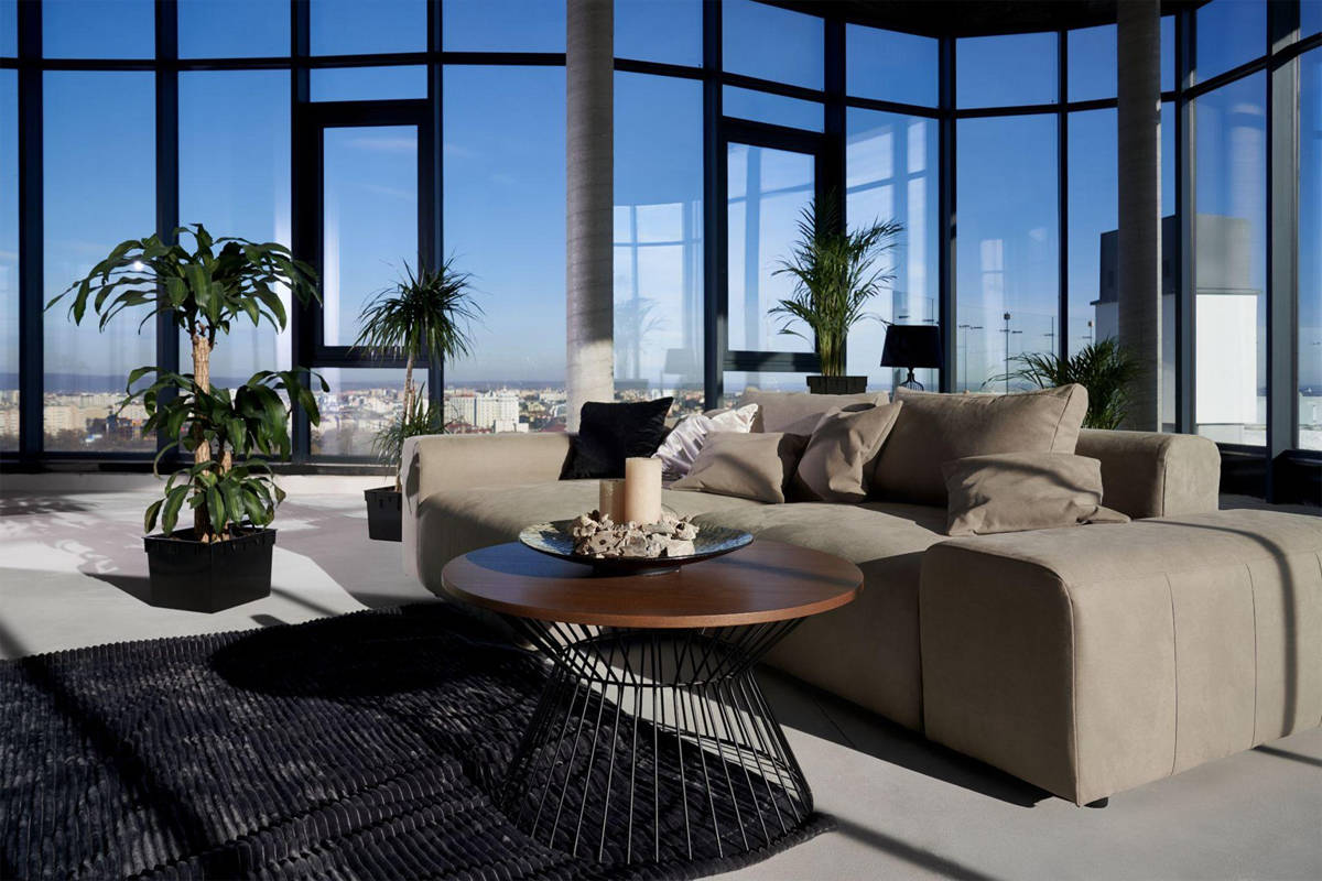 Apartamento tipo loft moderno con grandes ventanales y techos altos.